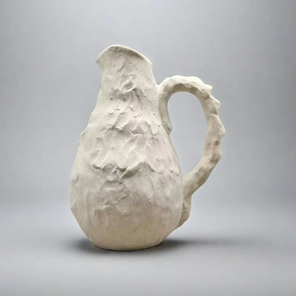 Off-white handmade irregular grain ceramic pitcher with a textured surface and organic handle for living room decorbites decor
