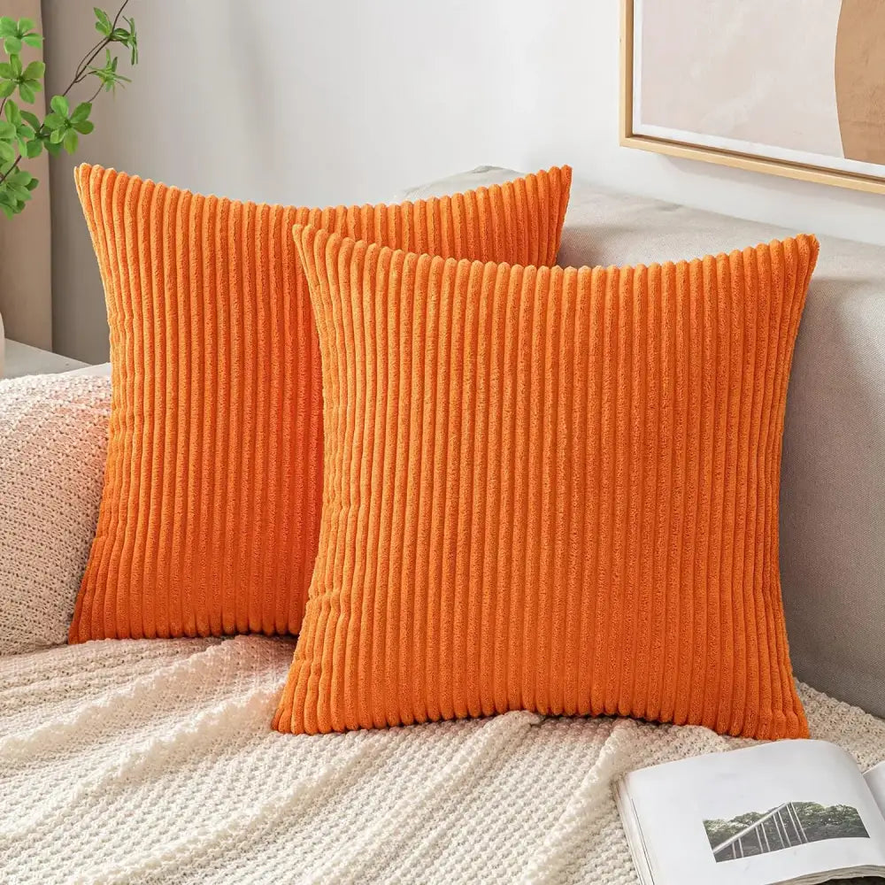 Vibrant orange ribbed corduroy striped throw pillow covers by decorbites neatly arranged on a cozy bed for living room decor