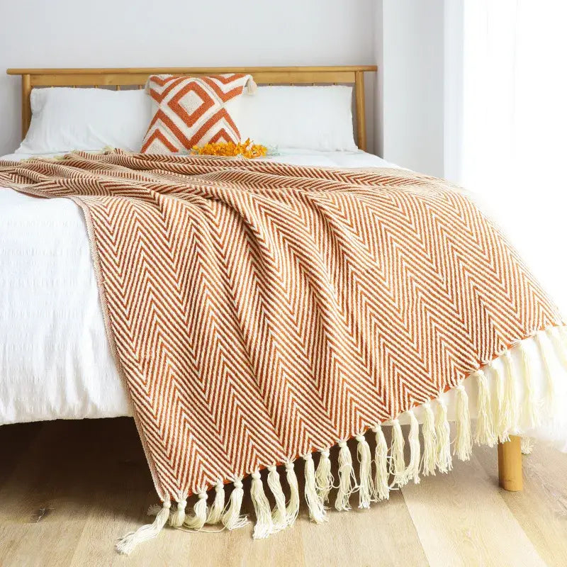 A cozy terracotta and cream herringbone decorbites geometric knitted blanket with soft fringed tassels for living room decor