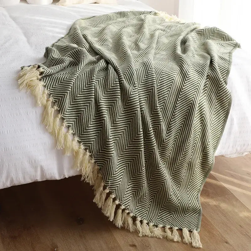 A soft olive green and cream decorbites geometric knitted blanket with herringbone pattern and fringed edges for living room decor