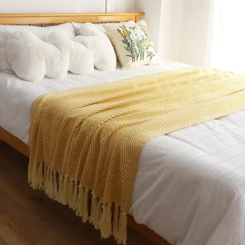 A soft mustard-yellow knitted blanket with herringbone weave and tassels perfect for decorbites geometric knitted throws