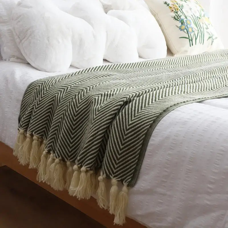 A soft olive green and cream decorbites geometric knitted blanket with herringbone pattern and fringed tassels for living room