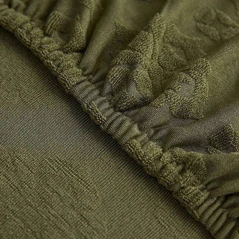 Olive green jacquard sofa seat cover with textured cable knit pattern and elasticated waistband for living room protection