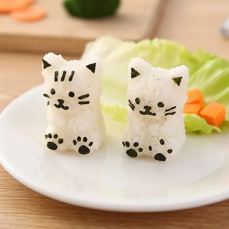 Two adorable white rice cat shape onigiri with black seaweed accents made using orange and white decorbites shape onigiri maker