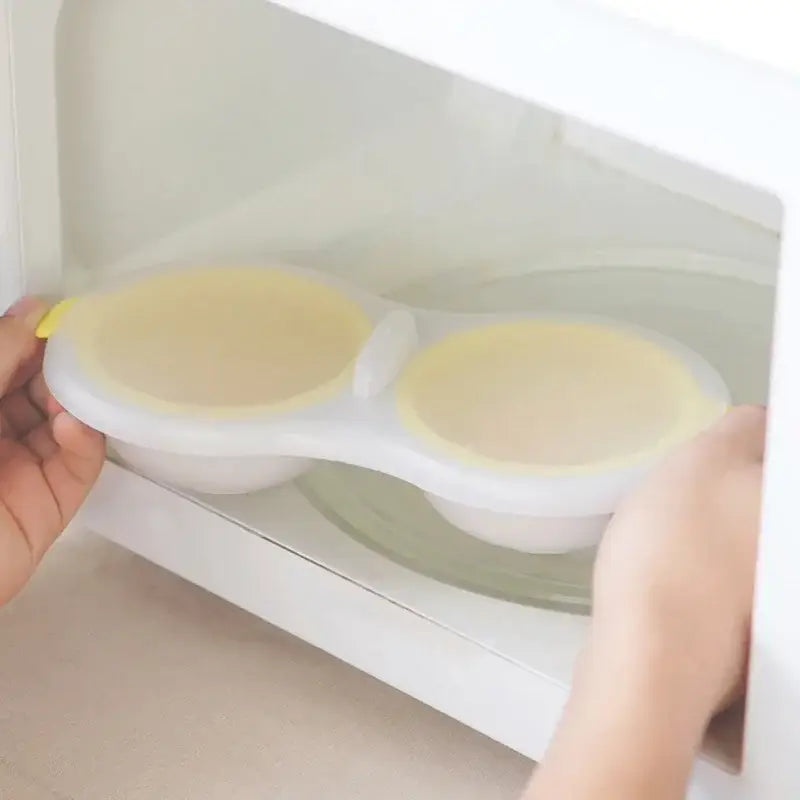 White silicone egg boiler steamer double cup with yellow lids and kitchen separator for convenient cooking
