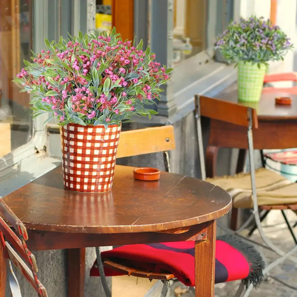 A vibrant pink flowering babysbreath lover fruit artificial plant in a red and white checkered ceramic pot for decor