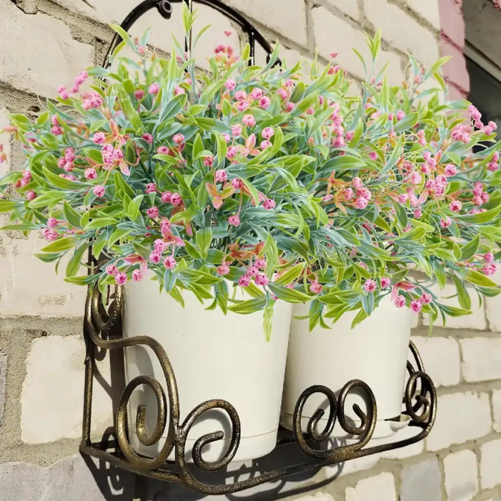 A wrought iron wall-mounted planter with two white ceramic pots holding artificial babysbreath lover fruit plants