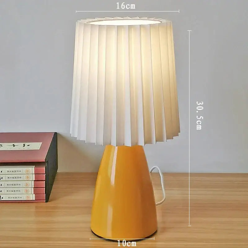 A warm yellow decorbites ceramic milkshake bedside lamp with pleated white fabric shade for bedroom decor