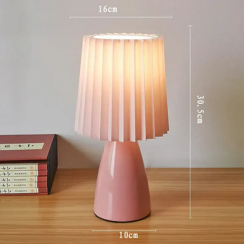 A soft pink decorbites ceramic milkshake bedside lamp with a pleated translucent shade for bedroom decor