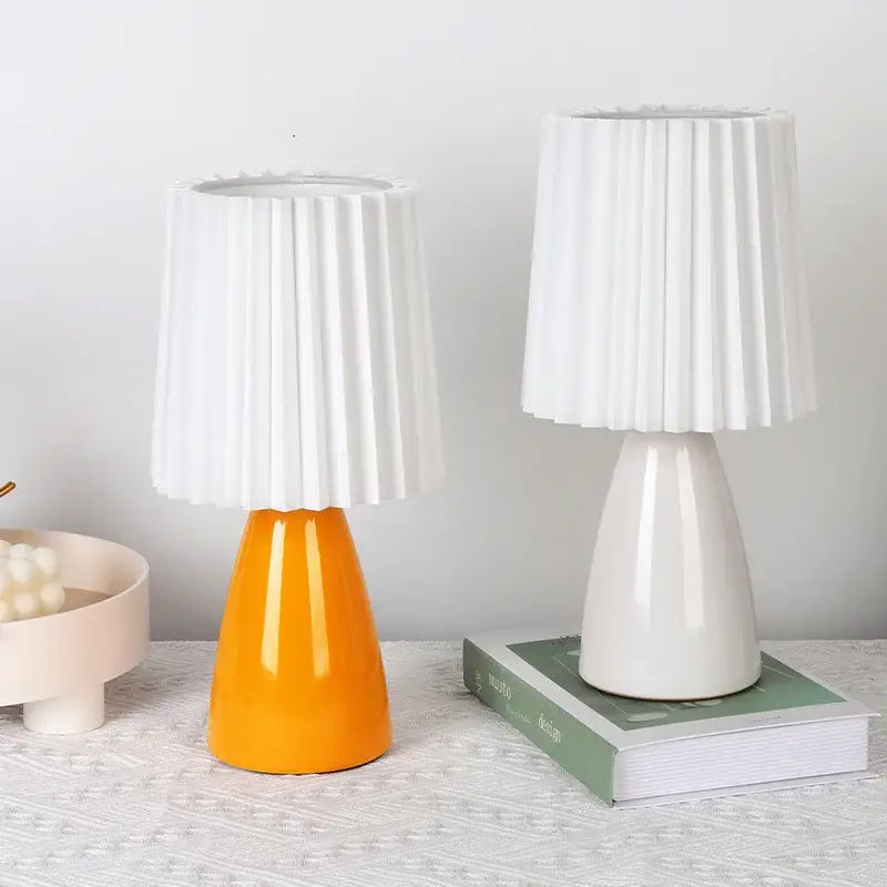Two decorbites ceramic milkshake bedside lamps with pleated white ceramic shades and glossy orange and off-white bases