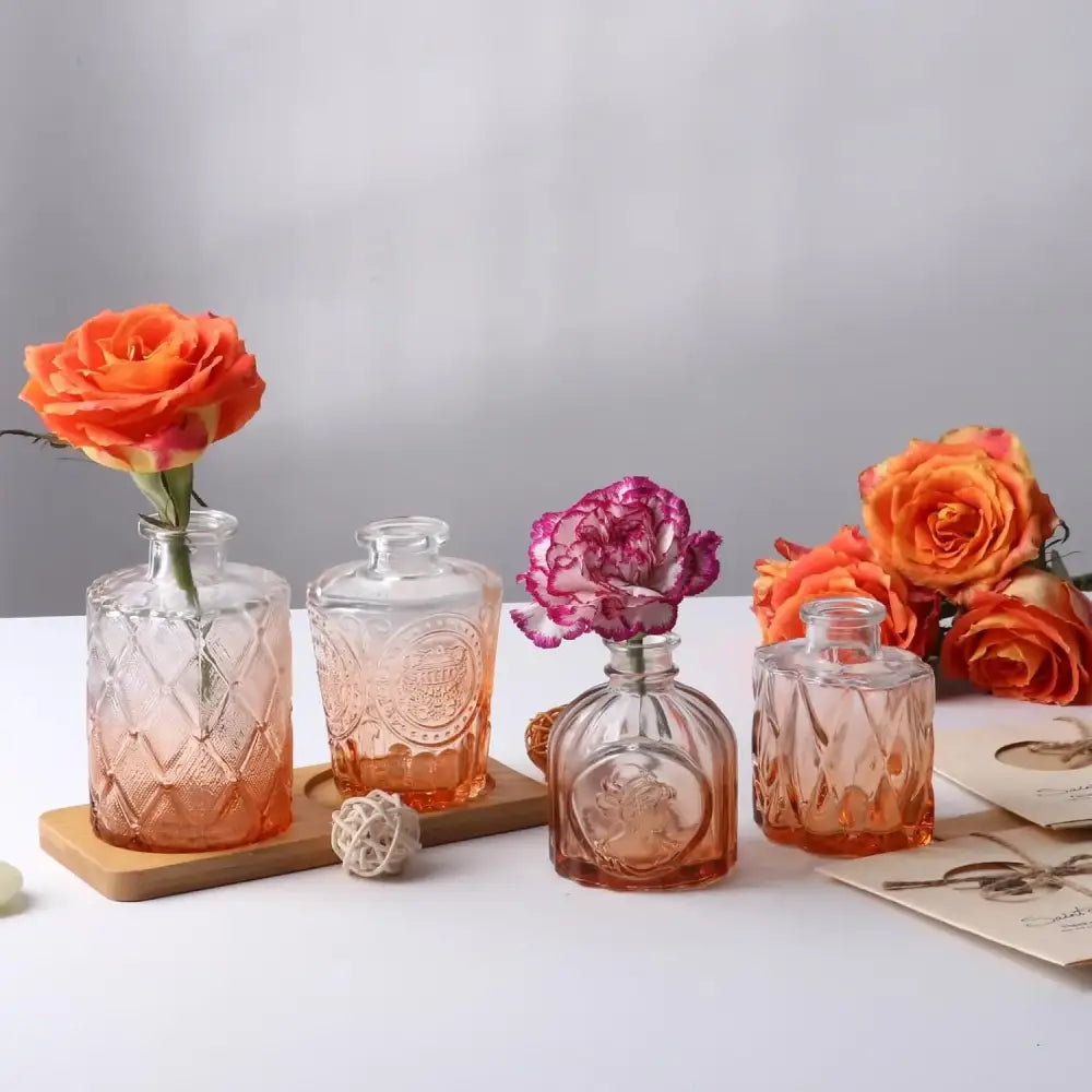 Set of four orange glass bud vases with embossed patterns holding single flowers for wedding centerpieces