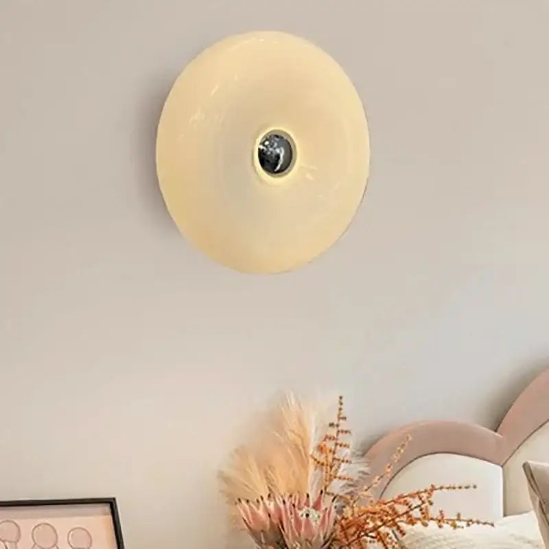 Cream-colored circular wall sconce with central metallic fixture decorbites glass donut led for bedroom lighting