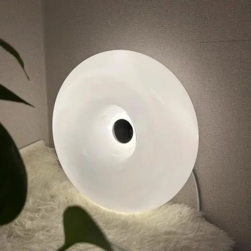 A sleek white glass donut led wall sconce with a matte finish and central black hole for bedroom lighting decorbites