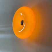 Orange glass donut led wall sconce featuring vibrant glossy glass donut with central black detail for bedroom lighting decorbites glass donut