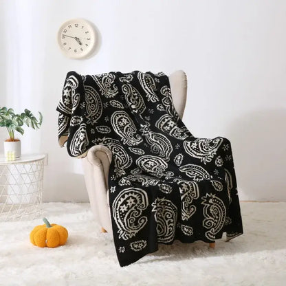 Black and white paisley knit throw blanket draped over chair featuring decorbites cashew pattern for living room use