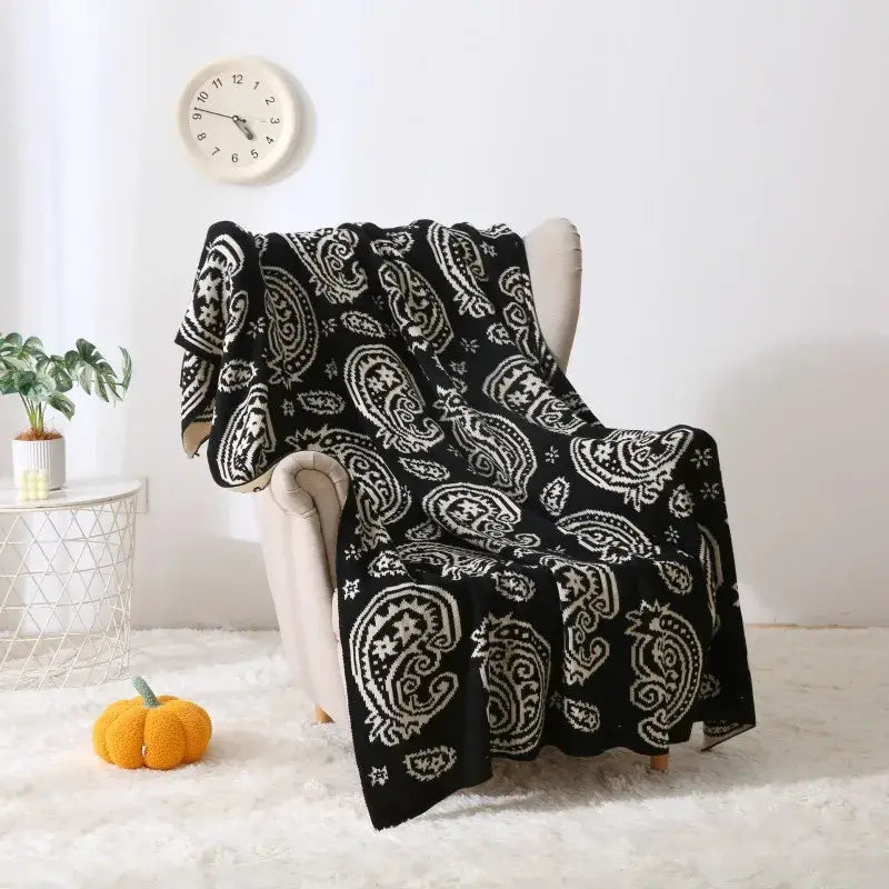 Black and white paisley knit throw blanket draped over chair featuring decorbites cashew pattern for living room use