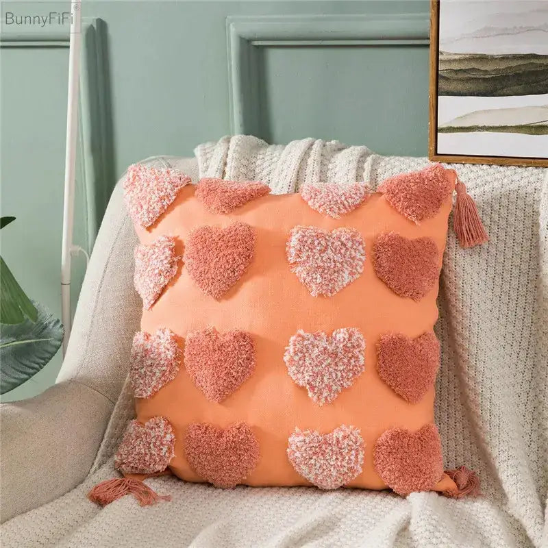 Coral-colored cushion cover with fluffy pink and white pom-pom hearts and tassels for decorbites heart embroidery decor