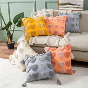 Cozy plush cushion covers in vibrant orange and grey with decorbites heart embroidery, tassels, and pom-pom accents