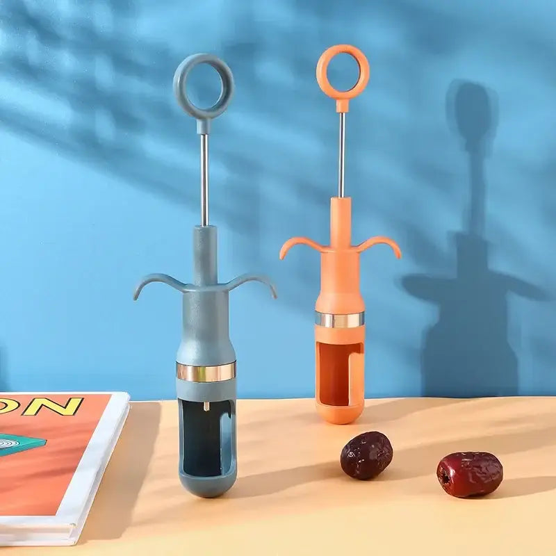 Two plastic cherry pitter fruit core removers in muted blue and vibrant orange with metallic ring handles and curved prongs