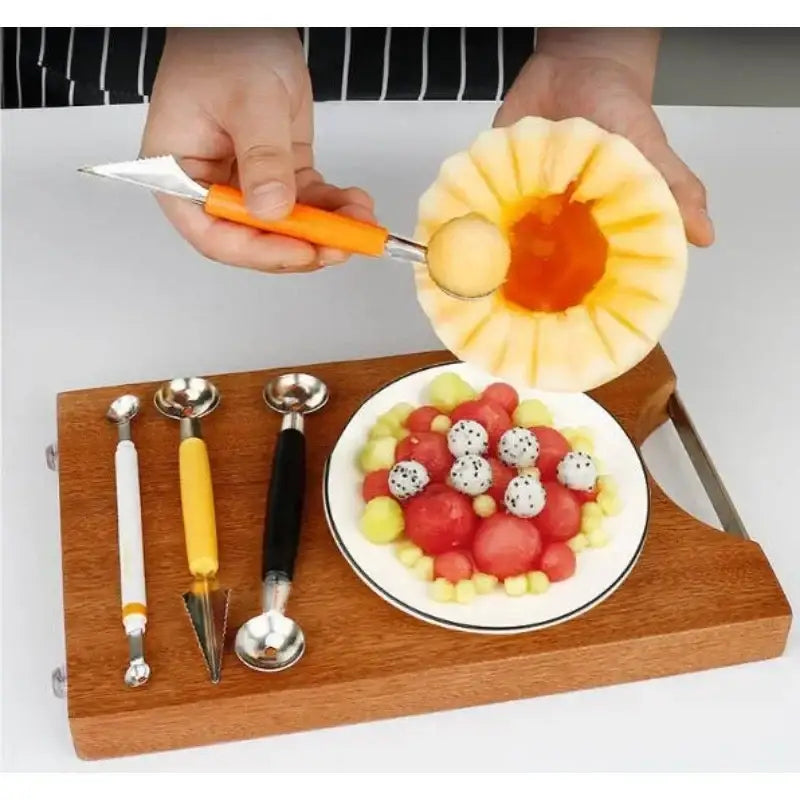 Orange stainless steel mini ball digger kitchen tool with orange handle scooping a mini ball from carved cantaloupe