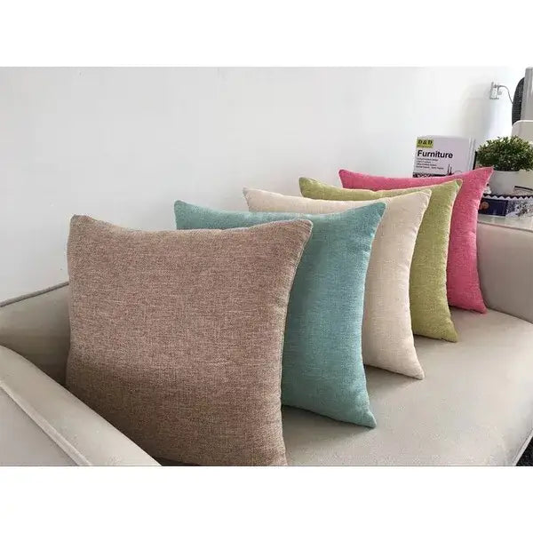 A set of orange textured linen cushion covers in muted earth tones on a decorbites ivory sofa cushion in living room decor