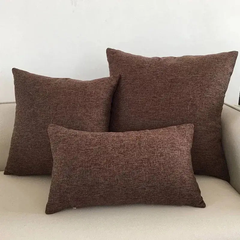 Set of three orange textured linen cushion covers in varying sizes on a decorbites ivory sofa cushion for living room decor