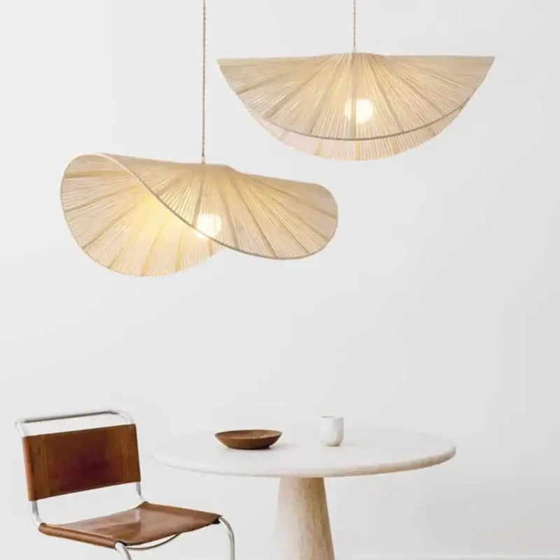 Two elegant light beige decorbites handmade rattan led pendant lights with fan-like design above dining table and chair