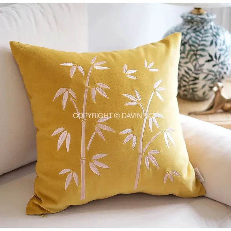 A mustard-yellow velvet pillow cover with delicate white decorbites bamboo embroidered fringed design for bedroom decor
