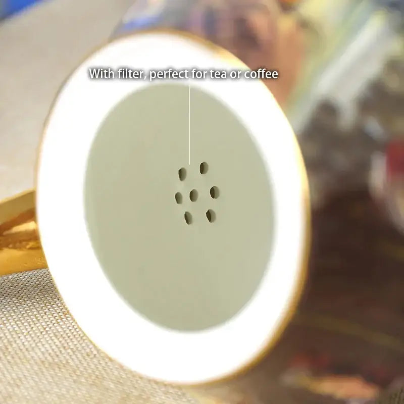 A white ceramic bone china tea filter with gold rim and perforations for straining from decorbites tea pot set