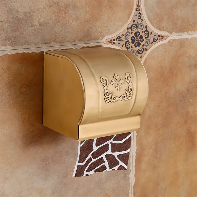 Gold-colored metal toilet paper holder with ornate floral embossing complements decorbites black carved bathroom rack