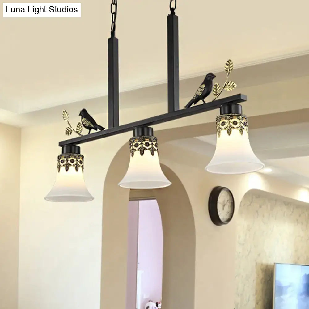 Black wrought iron DecorBites™ island pendant light with frosted glass shades and gold bird figurines for dining room