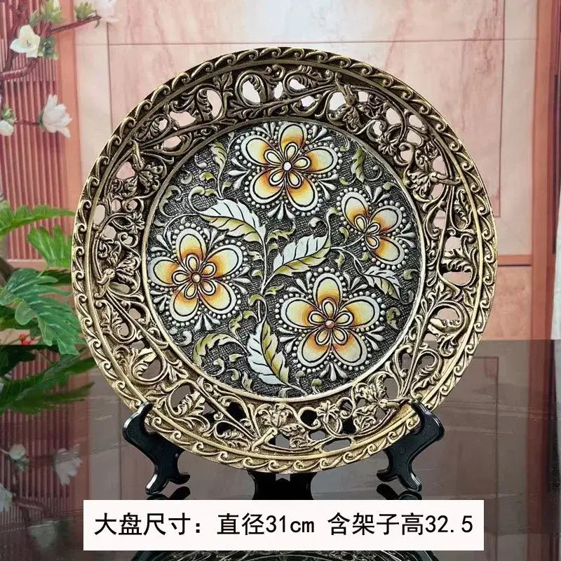 Ornate gold-toned metal decorative plate with intricate floral patterns complements black and gold resin vase dried flowers decor