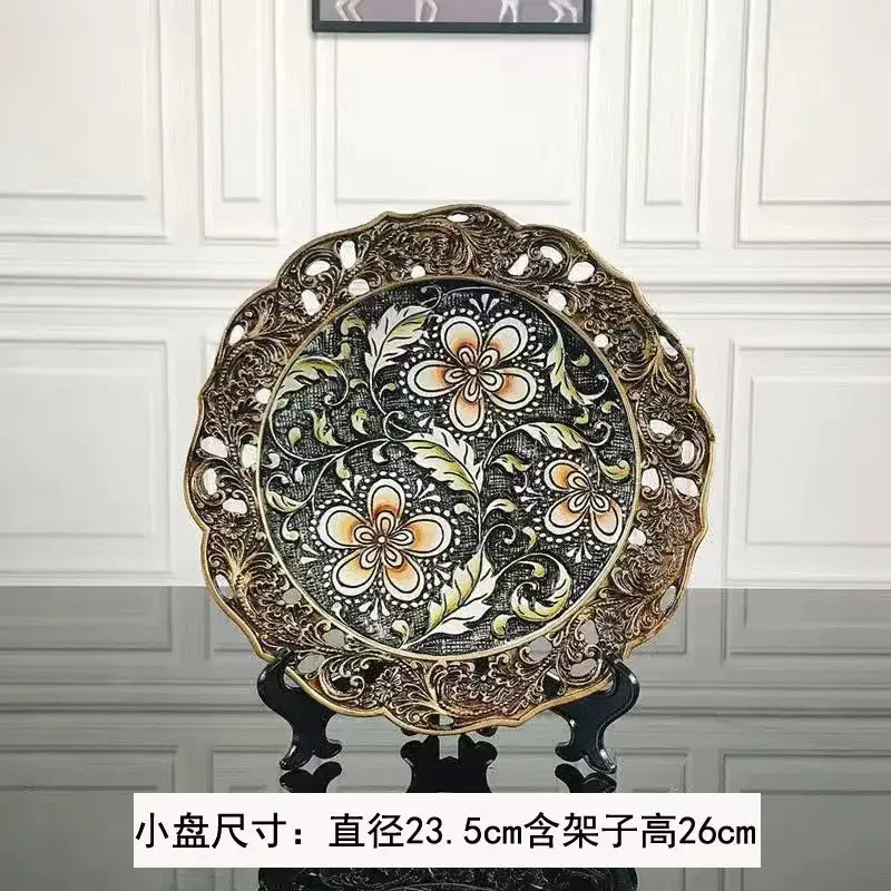 An ornate circular decorative plate with black center and gold border complementing resin vase dried flowers decor