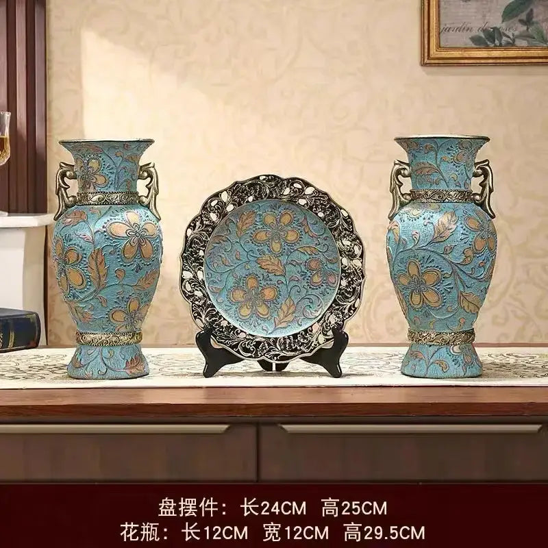 Pair of turquoise ceramic vases with gold floral patterns and bronze handles flanking ornate plate for dried flowers decor