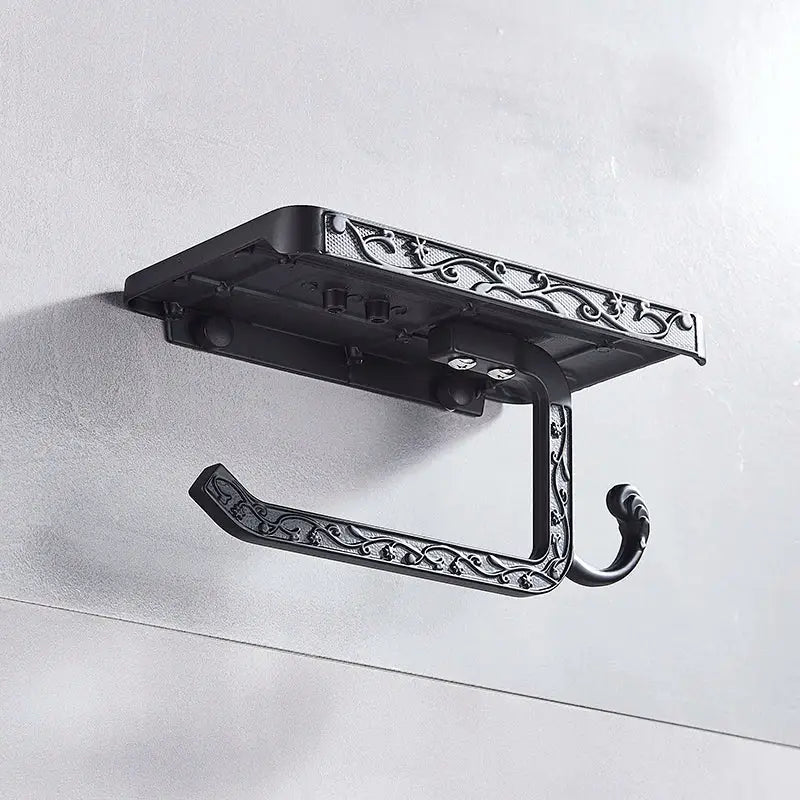 Ornate black metal toilet paper holder with intricate scrollwork design and phone shelf for bathroom storage