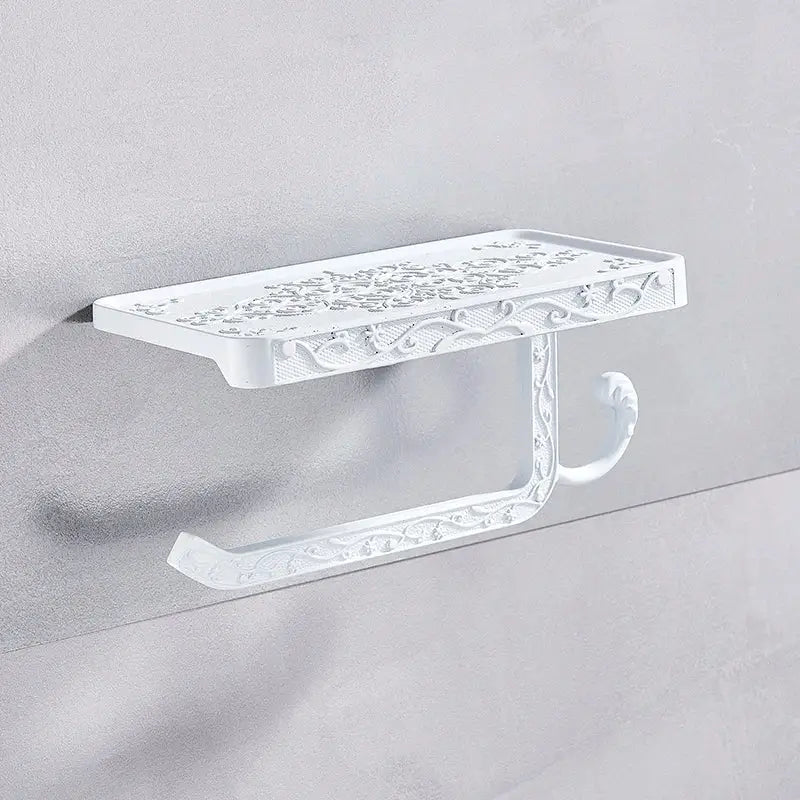 White ornate metal toilet paper holder with intricate floral scrollwork for bathroom storage with phone shelf