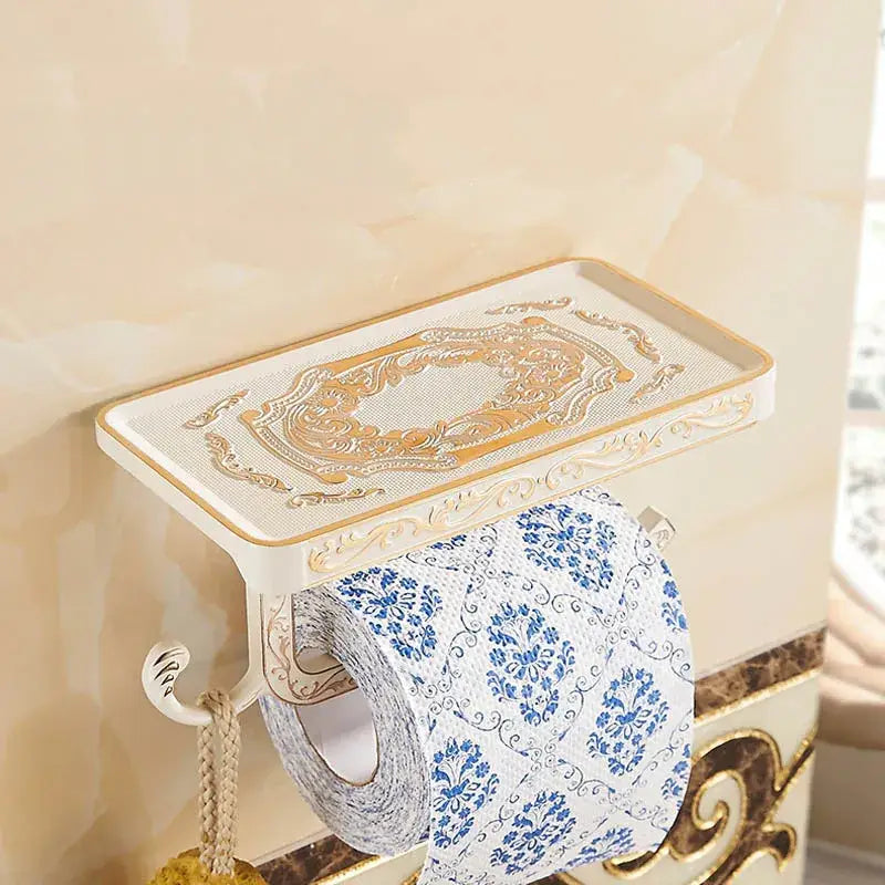 Cream-colored ornate metal toilet paper holder with gold detailing and decorative shelf for bathroom storage