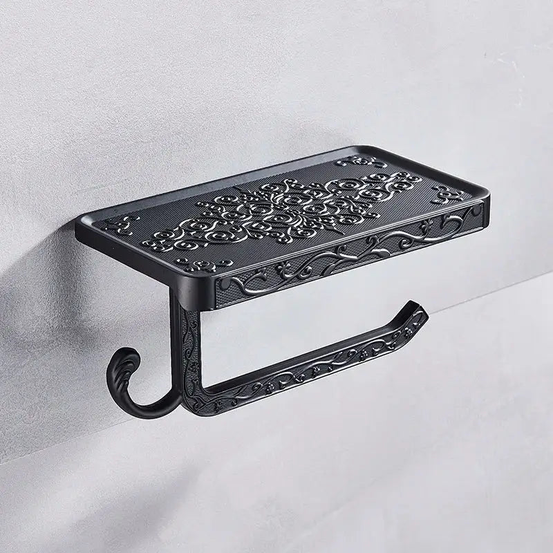 Ornate black metal toilet paper holder with intricate floral scrollwork and phone shelf for bathroom storage