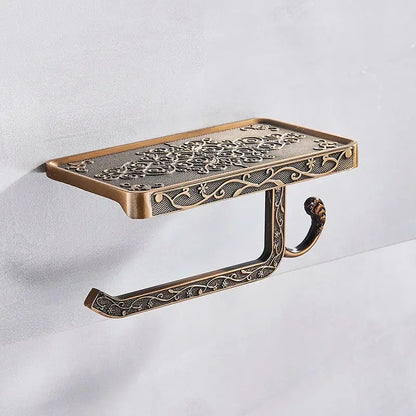 Antique brass toilet paper holder with ornate floral scrollwork and rectangular shelf for bathroom storage and phone