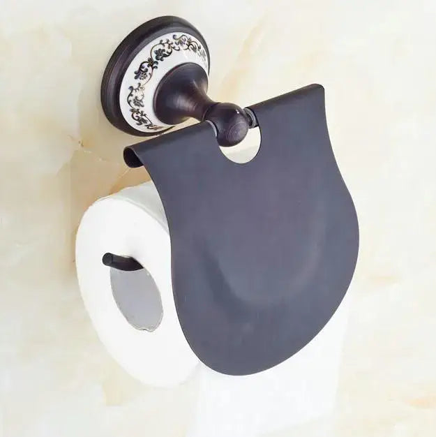 Black matte finished toilet paper holder with ornate white and black floral mounting plate in bathroom accessories set