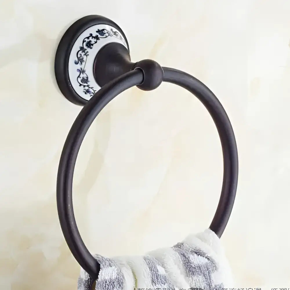 Ornate black metal towel ring with decorative white and blue floral ceramic backplate in bathroom accessories set