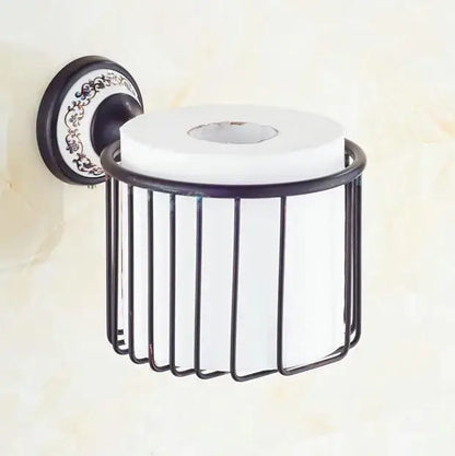 Black wrought iron toilet paper holder with ornate decorative plate and white roll in bathroom accessories set