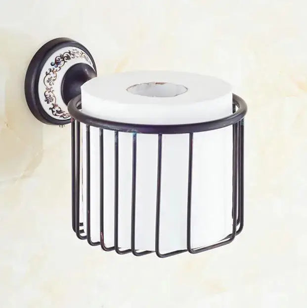 Black wrought iron toilet paper holder with ornate decorative plate and white roll in bathroom accessories set