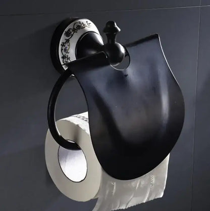 Ornate black and white bathroom accessories set featuring a black matte wrought iron toilet paper holder with decorative plate