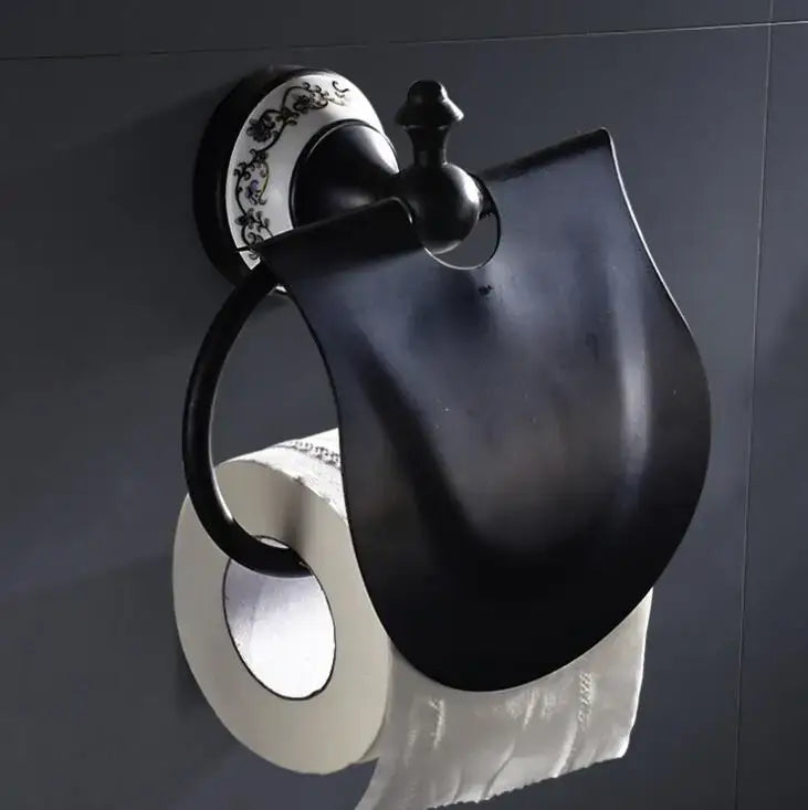 Ornate black and white bathroom accessories set featuring a black matte wrought iron toilet paper holder with decorative plate