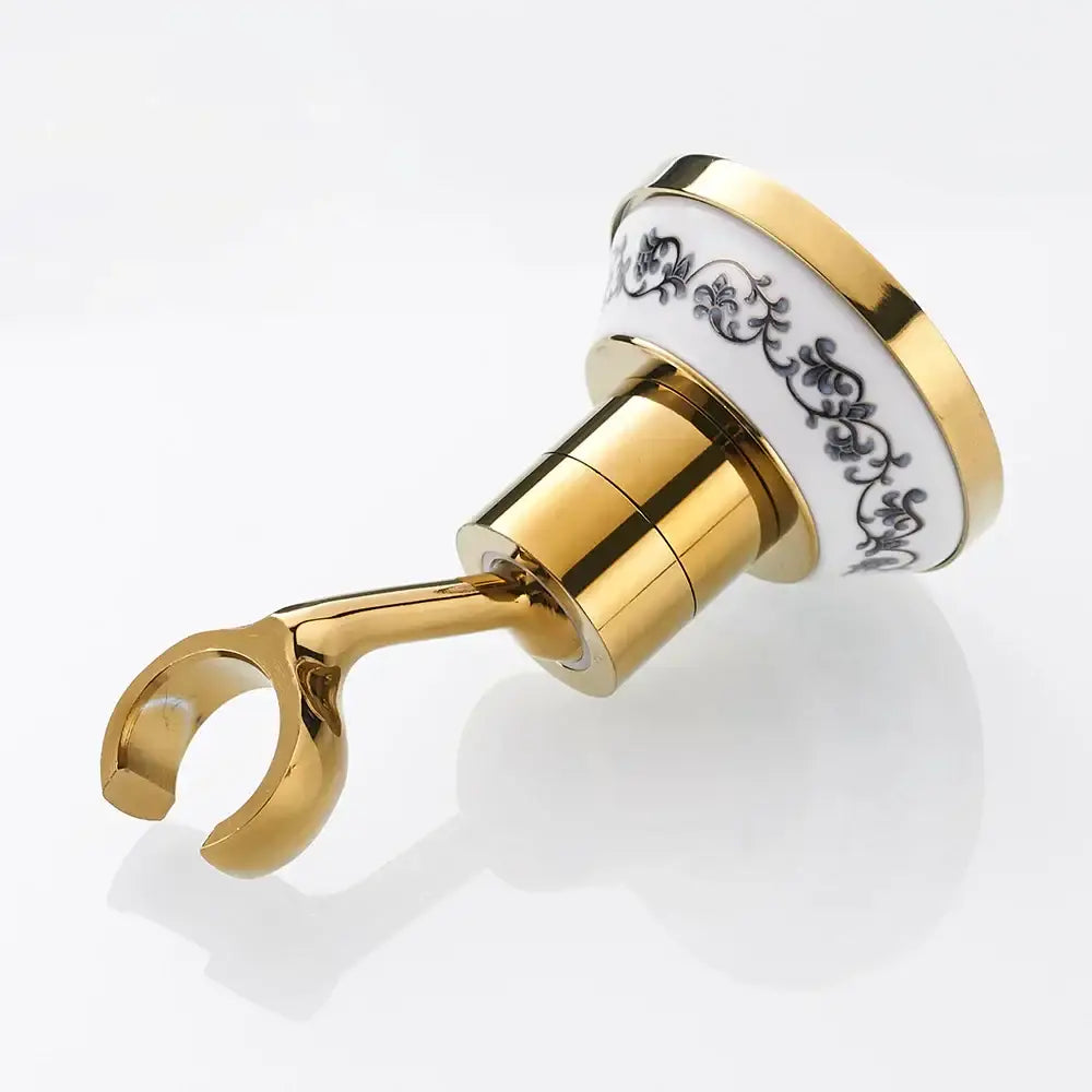 Gold-toned bathroom towel rack with white ceramic top black floral detailing and polished brass shower mount bracket