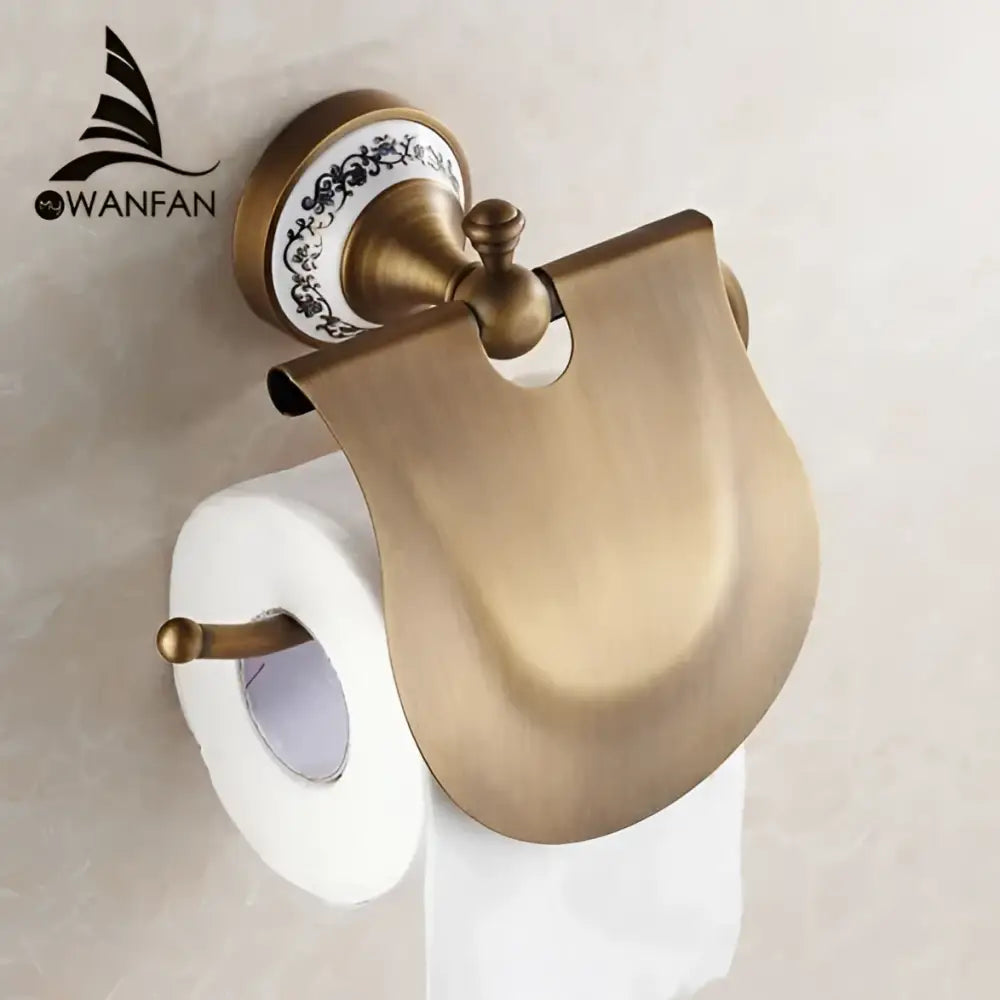Antique brass toilet paper holder with decorative white ceramic base and curved metal cover in bath hardware set