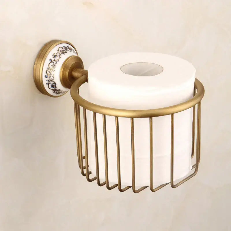 Antique brass toilet paper holder with decorative white ceramic backplate and vertical wire cage in bath hardware set