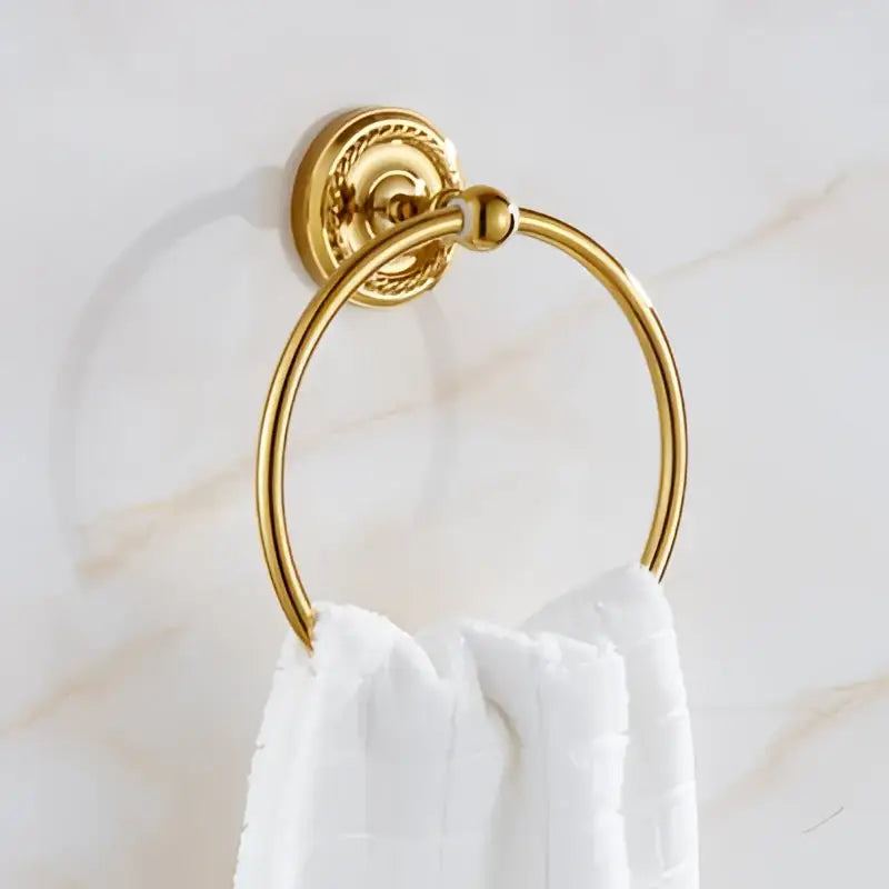 Gold-toned circular towel ring with ornate textured mounting plate in decorbites brass gold bathroom hardware set