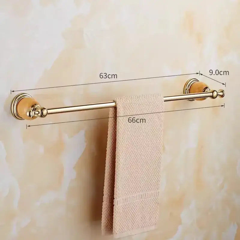 Gold-toned brass jade towel rack with ceramic end caps holding a beige textured towel from decorbites brass jade bathroom set